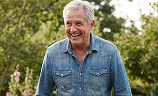 Smiling 65-year-old man looking content and active, living his best life as a result of longevity physical training.