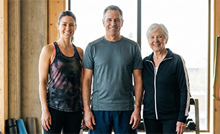 Medium shot of three capable individuals ranging from age 35 to 75 in workout gear, representing the target audience for longevity training.